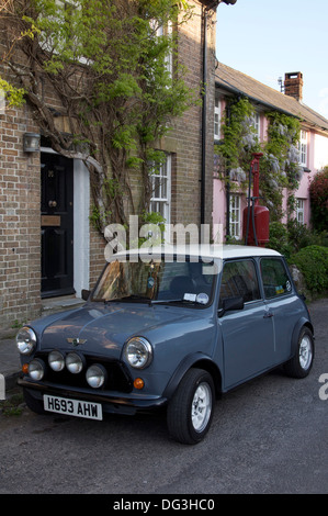 Oldtimer. Ein Austin Mini geparkt in der High Street von der malerischen Dorset Dorf Sydling St. Nikolaus. Dahinter befindet sich ein Vintage Zapfsäule. England. Stockfoto