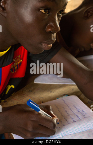 Senegal, Touba. Junge am Al-Azhar Madrasa, eine Schule für islamische Studien in arabischer Sprache in sein Notizbuch schreiben. Stockfoto