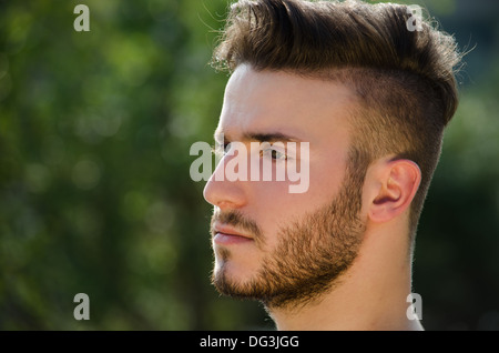 Porträt von hübscher junger Mann draußen in der Natur, auf einer Seite Stockfoto