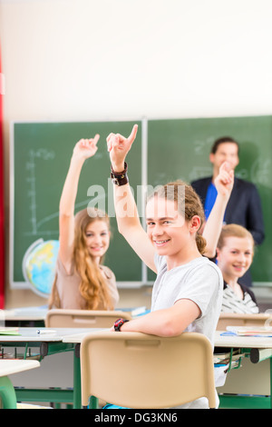 Klasse Lehrer geben Schulstunde vor einer Tafel oder Board Studenten oder Schüler, heben sie ihre Hände Stockfoto