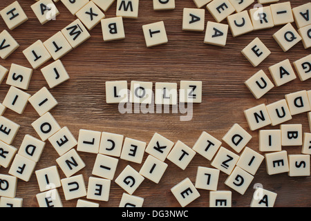 Plastische Buchstaben aus einem Kinder Rechtschreibung Spiel auf einem Holztisch buchstabieren "LOLZ" Stockfoto