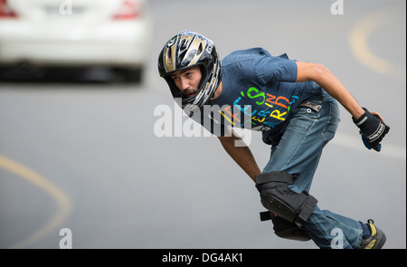 Skateboard Longboard Mann training Abfahrt auf öffentlichen Straßen mit einem Fahrzeug fahren im Hintergrund Stockfoto