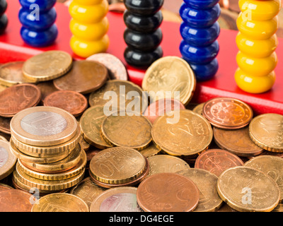 Ein Bündel von verschiedenen Euro-Münzen und Cent vor ein Abakus Stockfoto