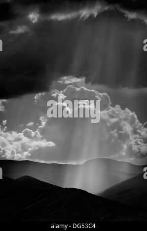 Sonnenlicht Strahlen aus den Wolken fallen auf dunkle Gebirge Stockfoto