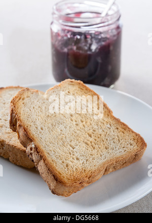 Teller mit Toast mit einem Marmeladenglas im Hintergrund Stockfoto