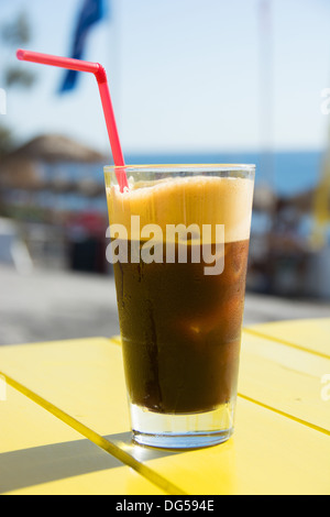 Ein kalter, Eiskaffee schaumigen Glas 'Espresso Fredo' schwarz auf eine Café-Tisch. Griechenland, 2013. Stockfoto