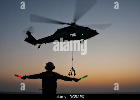 Ein US-Marine Seemann signalisiert einen MH-60 Seahawk-Hubschrauber auf dem Flugdeck des Flugzeugträgers USS George Washington während einer Auffüllung auf See 14. Oktober 2013 in den Gewässern westlich von der koreanischen Halbinsel zu landen. Stockfoto