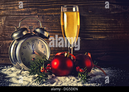 Weihnachtskugeln, ein Glas Champagner und Vintage Uhr fünf Minuten vor Mitternacht an Silvester. Stockfoto
