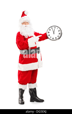 In voller Länge Portrait von einem lächelnden Weihnachtsmann zeigt auf eine Uhr Stockfoto