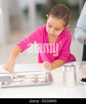 kleines Mädchen backen Kekse in Küche mit Elternteil Stockfoto