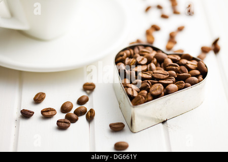 Kaffeebohnen in Herzform auf weißer Holztisch Stockfoto