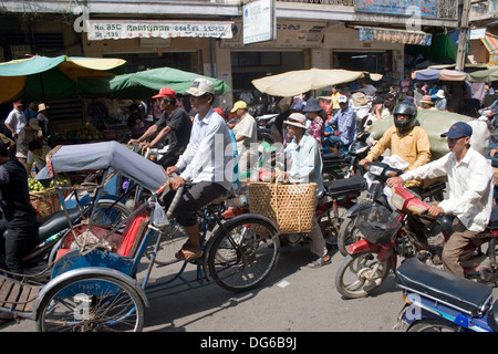 Auf einer belebten Straße in Phnom Penh, Kambodscha sind mehrere Cyclo-Fahrer zusammen mit Motorradfahrern hausieren. Stockfoto