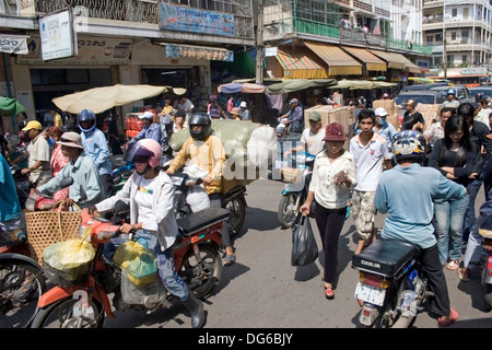 Auf einer belebten Straße in Phnom Penh, Kambodscha sind mehrere Cyclo-Fahrer zusammen mit Motorradfahrern hausieren. Stockfoto