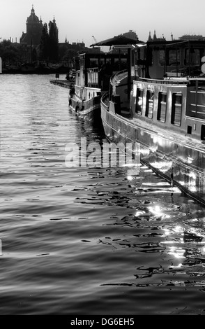 Boote Häuser auf Silber Amsterdam Gewässern gefangen von Oosterdokseiland Blick auf Saint Nicholas Church, Amsterdam, Niederlande. Stockfoto