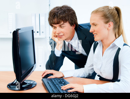 Lächelnd und junge Geschäftsleute arbeiten gemeinsam an den Computer. Bildschirm hat einen Beschneidungspfad. Stockfoto