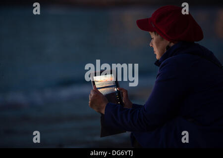 Aberystwyth Wales UK, 15. Oktober 2013 Frau mit ihrem Tablet-Computer, um den dramatischen Himmel in der Dämmerung über die Cardigan Bay am Strand bei Aberystwyth Wales UK zu fotografieren.  Nach einem warmen trocken und sehr sonnig Tag im Westen von Wales, ist die Prognose für die nächsten paar Due zur Steigerung der Wolke und Duschen der Regen Photo Credit: Keith Morris/Alamy Live-Nachrichten Stockfoto