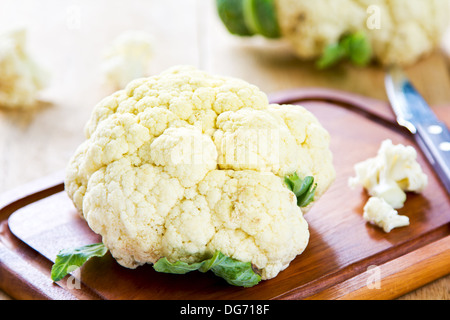 Frischer Blumenkohl mit Messer auf Schneidebrett Stockfoto