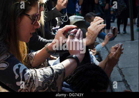 New York, USA. 15. Oktober 2013. Street-Art-Fans strömen in Stadtteil Tribeca New York auf Dienstag, 15. Oktober 2013, der fünfzehnte Ausgabe von Banksy-Graffiti-Kunst, "Tribecca" zu sehen. Die schwer fassbare Streetart-Künstler schafft Werke rund um die Stadt jeden Tag im Laufe des Monats Oktober und dieser Ausgabe zeigt eine Silhouette des World Trade Centers mit einer Blume befestigt. Bildnachweis: Frances Roberts/Alamy Live-Nachrichten Stockfoto