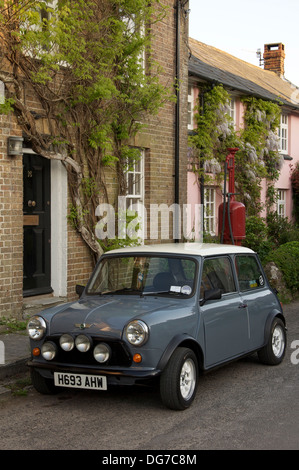 Oldtimer. Ein Austin Mini geparkt in der High Street von der malerischen Dorset Dorf Sydling St. Nikolaus. Dahinter befindet sich ein Vintage Zapfsäule. England. Stockfoto