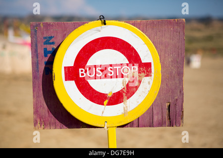 Roter Bus Stop-Schild montiert auf ein Stück Holz in der Mitte von Nirgendwo mit einem blauen Himmel im Hintergrund Stockfoto