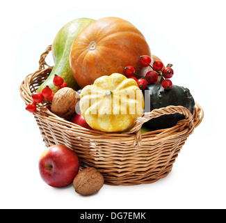 Frische reife Kürbisse, Äpfel, Trauben und Nüssen in Weidenkorb isoliert auf weiss Stockfoto