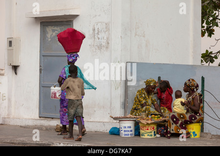 Senegal St. Louis. Straßenszene. Fußgänger gehen Frauen Verkauf von Nüssen und Früchten. Stockfoto