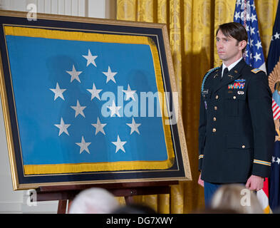 William Swenson, einem ehemaligen aktiven Dienst Armee Kapitän, der die Medal Of Honor für auffallende Tapferkeit verliehen wird, hört zu, als US-Präsident Barack Obama Bemerkungen im East Room des weißen Hauses in Washington, DC am 14. Oktober 2013 macht. Kapitän Swenson akzeptiert die Medal Of Honor für seinen mutigen Taten während seiner Tätigkeit als Embedded Trainer und Mentor der afghanischen nationalen Sicherheitskräfte mit afghanischen Grenze Mentor Polizeiteam, 1. Bataillon, 32. Infanterie-Regiment, 3rd Brigade Combat Team, 10th Mountain Division während der Kampfhandlungen in der Provinz Kunar, Afghanistan auf Stockfoto