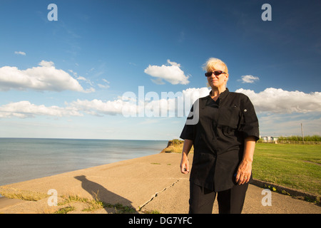 Sylvia Hughes steht neben den Rand des einstürzenden Steilküsten am Aldbrough auf Yorkshires Ostküste, UK. Stockfoto