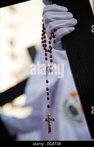 Büßer tragen ein Kreuz und einen Rosenkranz, Palmsonntag, Sevilla, Spanien Stockfoto