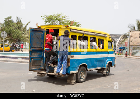 Senegal St. Louis. Junge Männer stehen oft auf dem Trittbrett an der Rückseite des lokalen Minibusse, die Bereitstellung von städtischen Nahverkehrs. Stockfoto