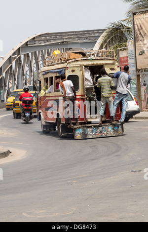 Senegal St. Louis. Junge Männer stehen oft auf dem Trittbrett an der Rückseite des lokalen Minibusse, die Bereitstellung von städtischen Nahverkehrs. Stockfoto