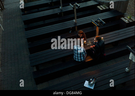 Männer sitzen, trinken auf Bänken an Tischen im freien bar Restaurant, am Abend, Brighton Stockfoto