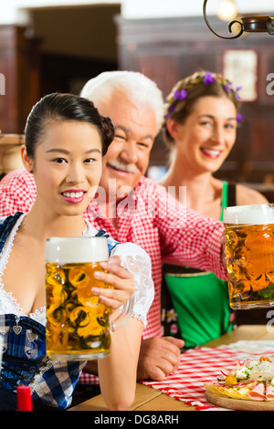 Im Pub - Freunde in Tracht, Dirndl und Lederhosen ein frisches Bier in Bayern, Deutschland Stockfoto