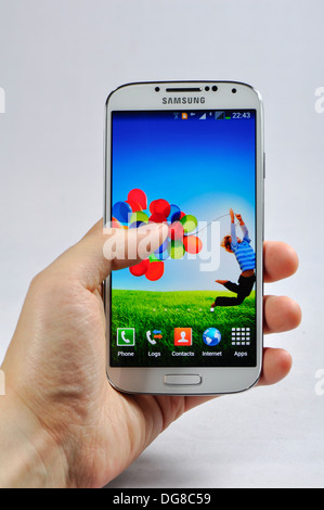 Junger Mann hält das neueste Samsung Handy Galaxy S4 zeigt die Frontansicht. Stockfoto