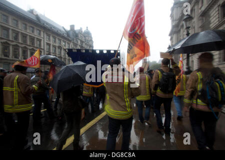 London UK. 16. Oktober 2013. Ein Feuerwehrmann mit Fahnen und Flaggen aus der Feuerwehr-Union marschieren durch Regen nach unten Whitehall Protest gegen Regierung Kürzungen und Sparmaßnahmen Credit: Amer Ghazzal/Alamy Live-Nachrichten Stockfoto