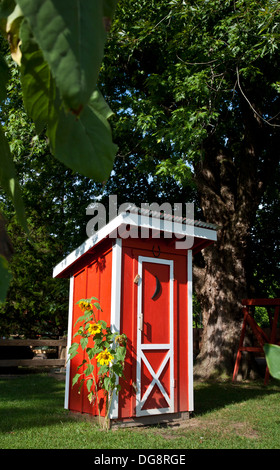 Farbenfrohe, leuchtend rote Nebengebäude mit einem Viertelmond im Sommer mit Sonnenblumen auf einer Farm, New Jersey, USA, Holzgartenlagerwerkzeug Schuppen pt Stockfoto