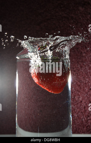 Erdbeere, fiel in ein Glas Wasser einen Spritzer erstellen Stockfoto