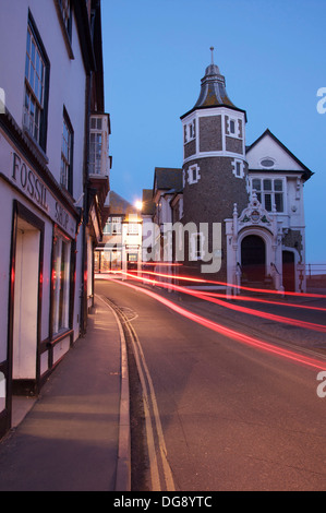 Jurassic Coast. Die malerische historische Lyme Regis Guildhall. Autoscheinwerfer sind entlang der engen und verwinkelten Bridge Street Schlieren. Dorset, England, Vereinigtes Königreich. Stockfoto