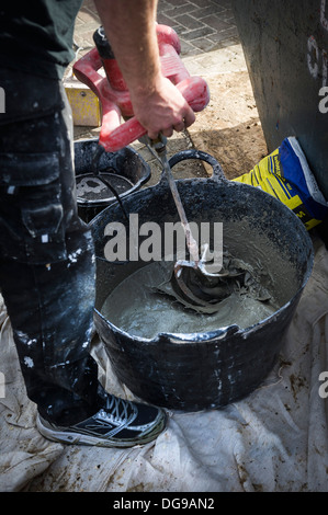 Ein Arbeiter mit einem Elektrowerkzeug Beton mischen Rendern in einer Wanne. Stockfoto
