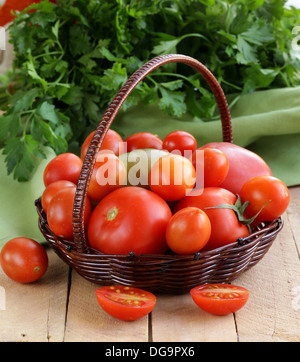 Korb mit verschiedenen Arten von Tomaten auf Holztisch Stockfoto