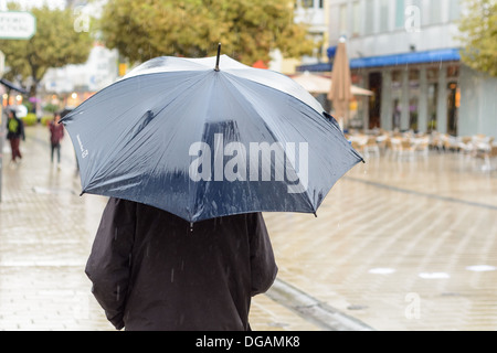 Fußgänger mit blauen Schirm Trog der Regen in der Innenstadt Fußgängerzone Sülmer City, Heilbronn, Deutschland Stockfoto