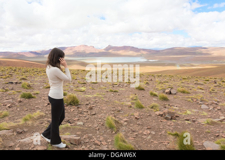 Frau am Handy und Enjoing Panorama des bolivianischen Altiplano mit Lagune Morejon, Bolivien Stockfoto
