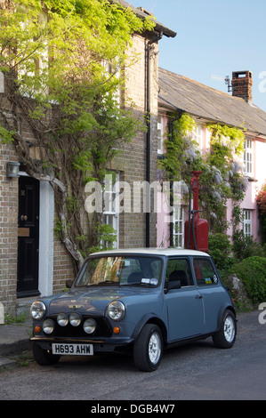 Oldtimer. Ein Austin Mini geparkt in der High Street von der malerischen Dorset Dorf Sydling St. Nikolaus. Dahinter befindet sich ein Vintage Zapfsäule. England. Stockfoto