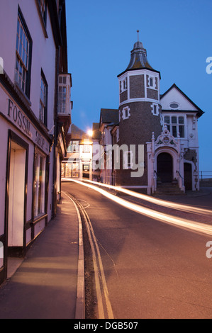 Jurassic Coast. Die malerische historische Lyme Regis Guildhall. Autoscheinwerfer sind entlang der engen und verwinkelten Bridge Street Schlieren. Dorset, England, Vereinigtes Königreich. Stockfoto