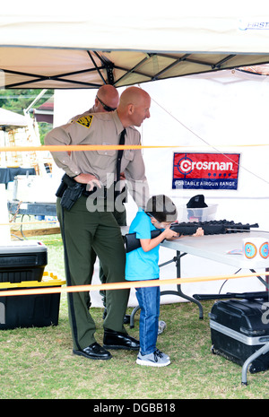 Officer Ritzheimer von North Carolina Wildlife Resources Commission hilft einen jungen Mann ein Luftgewehr schießen. Stockfoto