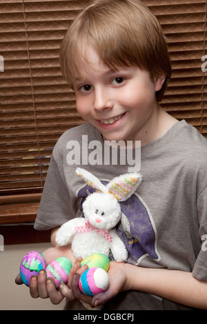 Junge hält seine neu gefärbten Ostereier und Plüschhase 11 Jahre alt. St Paul Minnesota MN USA Stockfoto