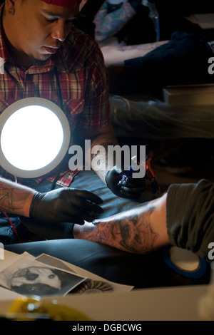 Ein Tattoo-Künstler Farb / Tätowierung ein Personen-Bein Stockfoto