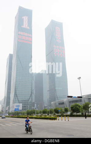 Riesige neue Wolkenkratzer Gewerberäume in China; im Vordergrund fährt eine Person ein elektrisches Motorrad durch den Dunst Stockfoto