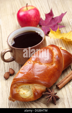 Brötchen, Kaffee und Apfel auf Holztisch Stockfoto