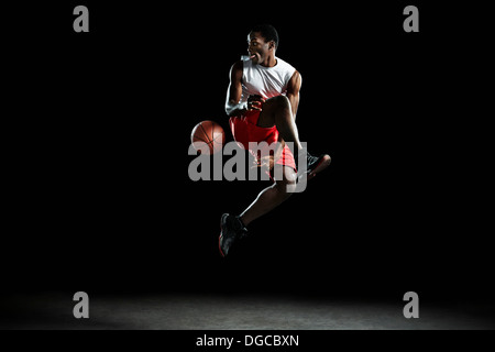 Junge männliche Basketballspieler Mitte Luft Stockfoto